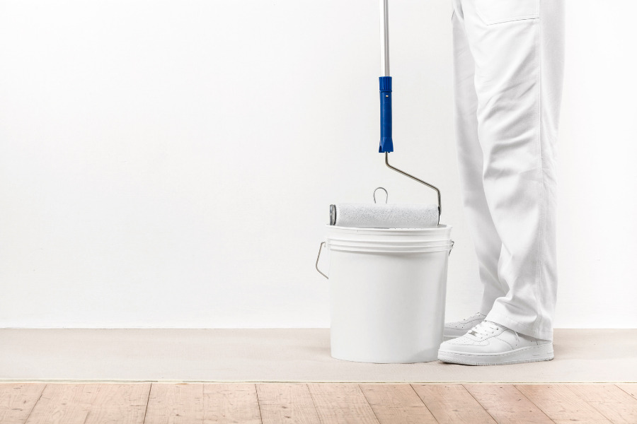picture of a man with a paint roller and bucket ready to start an interior wall painting job